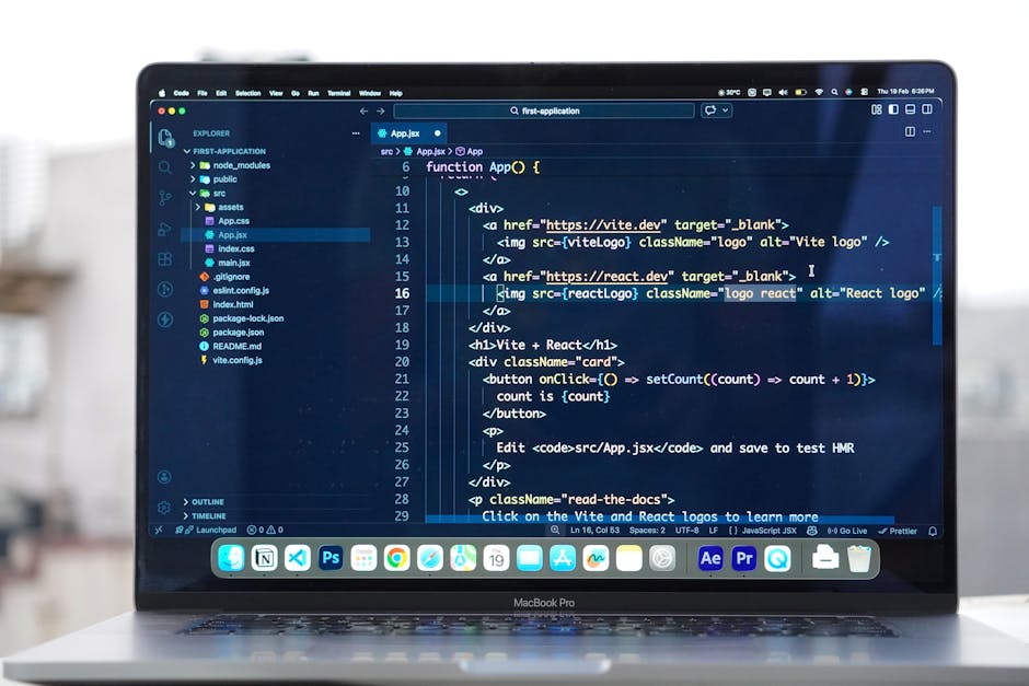 Close-up view of a MacBook laptop displaying a dark-themed coding interface with lines of HTML, JavaScript, and React code. The screen features a code editor with syntax highlighting, showing tags, fu